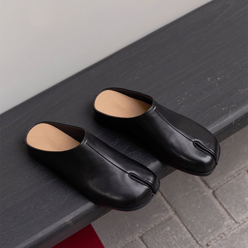 Pantuflas informales de piel con puntera dividida, planas y sin tal&oacute;n, en negro y rojo