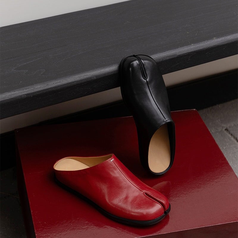 Pantuflas informales de piel con puntera dividida, planas y sin tal&oacute;n, en negro y rojo