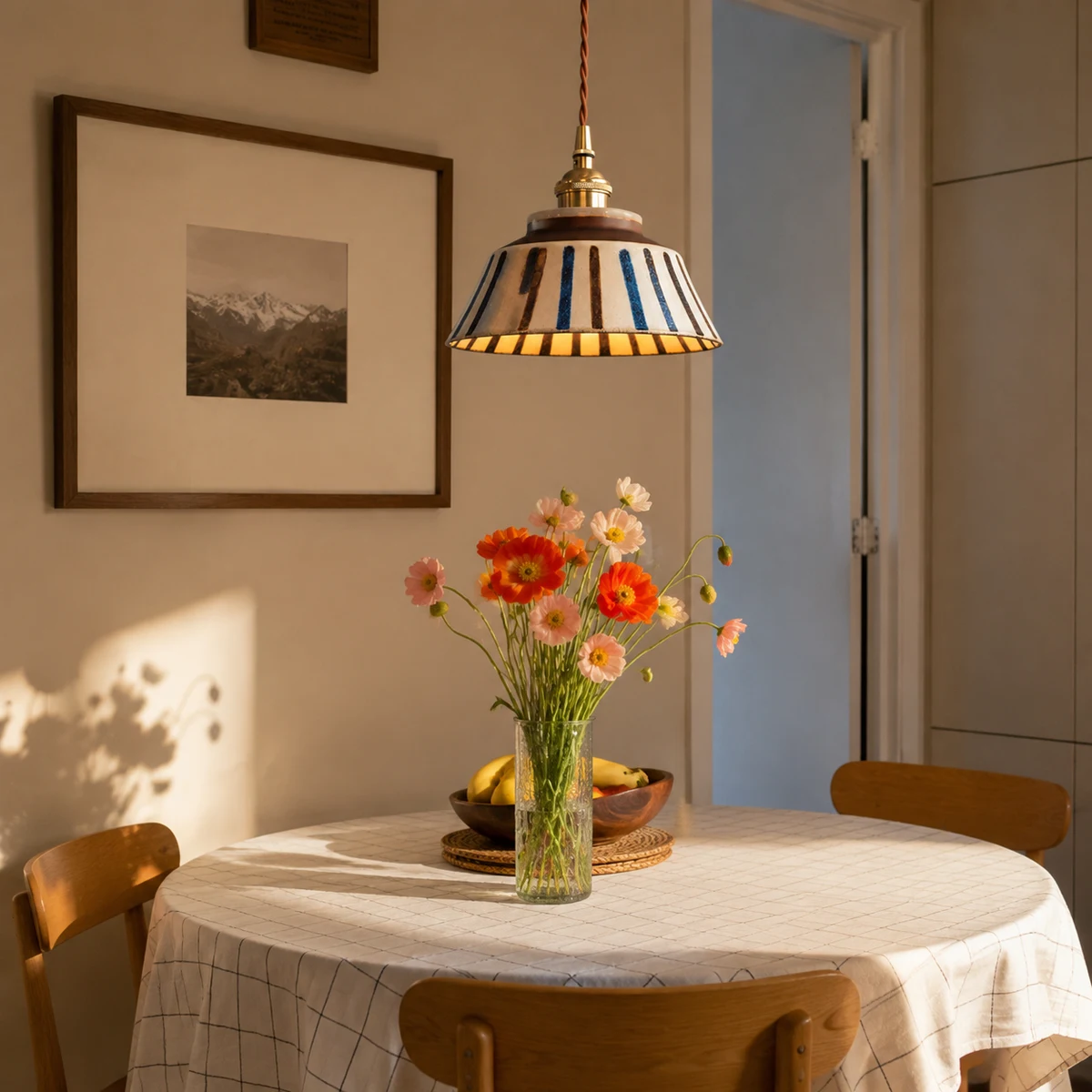 Striped ceramic pendant lamp above a round dining table with flowers